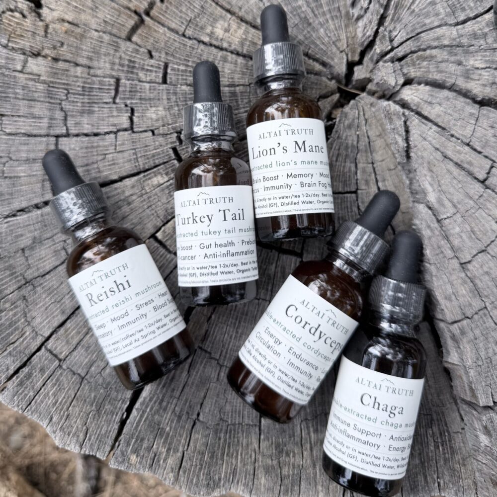 Altai Truth mushroom tinctures on natural wood surface — Lion’s Mane, Reishi, Chaga, Cordyceps, Turkey Tail wellness extracts.